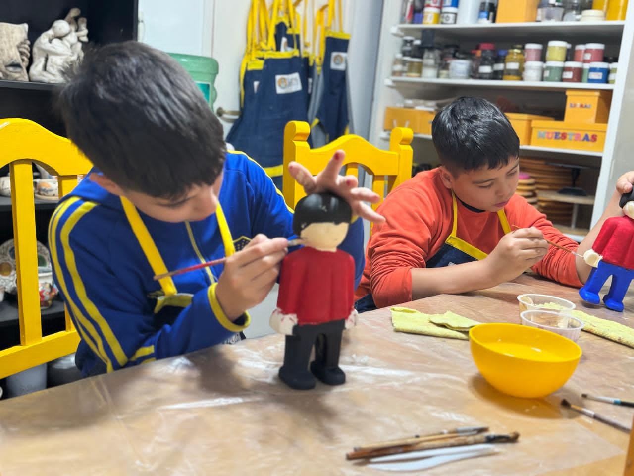 dos niños pintando piezas de ceramica